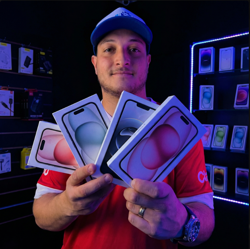 Dono da Referência Cell segurando iPhones na loja